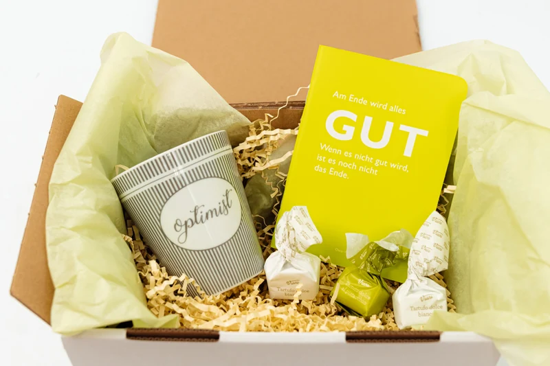 Geschenkbox "Optimist" mit Tasse, Notizbuch und süßer Nervennahrung